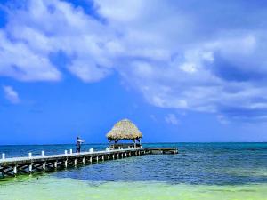 un hombre parado en un muelle en el océano en Miramar Villas Resort en San Pedro