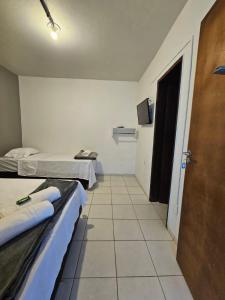 a small room with two beds and a door at Lofts Visconde in Joinville