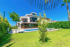 ein großes weißes Haus mit einer Palme im Hof in der Unterkunft Paradise Town Villa Estella in Belek