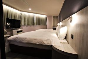 a bedroom with a white bed and a television at Golden Home Hotel in Taipei
