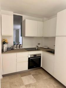 a kitchen with white cabinets and a black dishwasher at Only One Piccolo Pevero in Arzachena