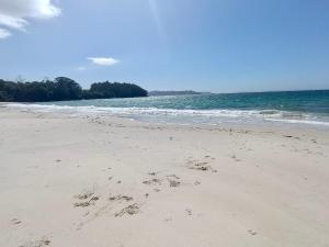 a beach with footprints in the sand and the ocean at El Mirador de playa LAPAMAN - BUEU in Marín