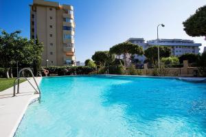 a large blue swimming pool in a city at Great location! Walking distance to everything! in Fuengirola