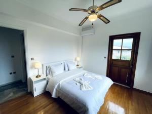 - une chambre blanche avec un lit et un ventilateur de plafond dans l'établissement Orange Blossom Villa, à Naupacte