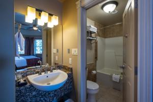 a bathroom with a sink and a toilet and a bed at Kaslo Hotel in Kaslo