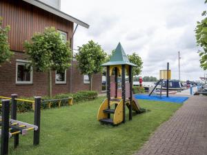 un parque infantil en un patio junto a un edificio en Tiny houseboat Parel I - airco, en Uitgeest