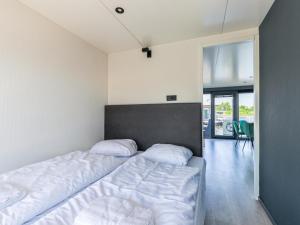 um quarto com uma cama com lençóis brancos e uma cabeceira em Tiny houseboat Parel I - airco em Uitgeest