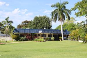 a house with palm trees in front of it at Country Road Motel in Charters Towers