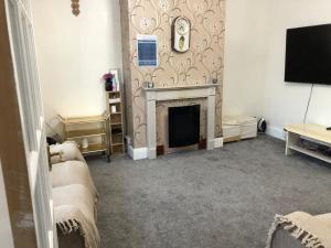a living room with a fireplace and a flat screen tv at Holiday inn house in Longton