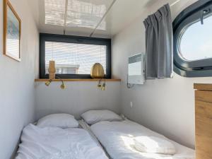 two beds in a small room with a window at Tiny Houseboat De Woudaap - I in Uitgeest