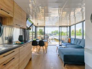 uma cozinha e sala de estar com um sofá azul em Tiny Houseboat De Woudaap - I em Uitgeest