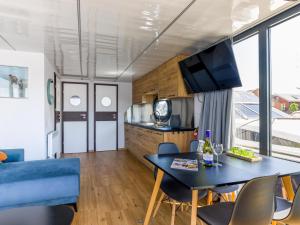 uma cozinha e sala de estar com mesa e cadeiras em Tiny Houseboat De Woudaap - I em Uitgeest
