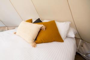 a bed with several pillows on top of it at Pure Glamping Guilderton in Guilderton +13 photos