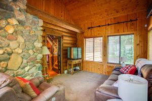 een woonkamer met een stenen open haard in een blokhut bij Lakefront Cabin Retreat, 2-Acre Lot with Deck! 