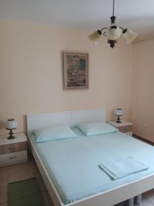 a bedroom with a large white bed with two lamps at Apartment Seget Vranjica 1051b in Seget Vranjica