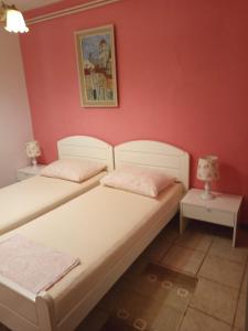 two beds in a room with a red wall at Apartment Seget Vranjica 1051b in Seget Vranjica