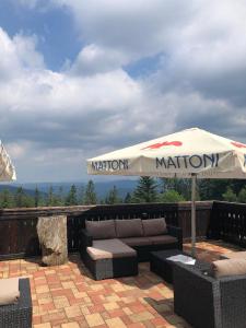 eine Terrasse mit einem Sofa und einem Sonnenschirm in der Unterkunft Horský hotel Hájenka in Makov