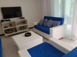 uma sala de estar com um sofá e uma televisão em Apartamento Particular de 03 suítes, Resort Treebies, Praia de Subauma - Ba em Entre Rios