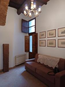 een woonkamer met een bank en een kroonluchter bij Charming apartment in medieval tower in Spoleto