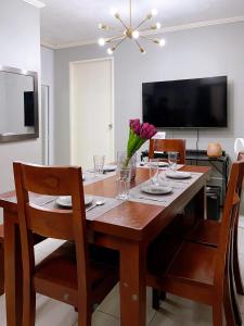 uma sala de jantar com uma mesa com cadeiras e uma televisão em The Doll House 1 em Orani