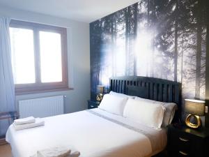 - une chambre avec un grand lit blanc et une fresque murale dans l'établissement Especial Familias Golden - Soldeu - Parking Gratis, à Soldeu