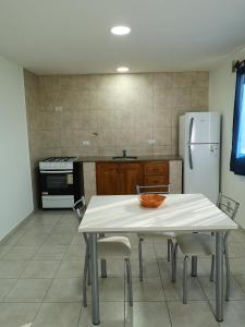 a kitchen with a white table with chairs and a refrigerator at Departamento amplio y luminoso in Esquel