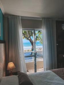 a bedroom with a bed and a view of the beach at Pousada Vô Jaques in Porto Belo