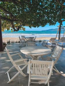 una mesa y sillas en una playa con el océano en Pousada Vô Jaques, en Porto Belo