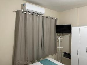 a room with a bed with a curtain and a television at Apto Centro Catedral in Santa Cruz do Sul