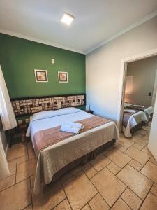 1 dormitorio con cama y pared verde en Pousada Vô Jaques, en Porto Belo