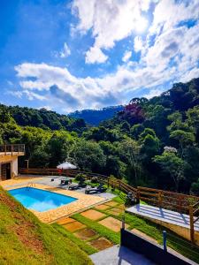 una casa con piscina y montañas al fondo en Pousada Olivier da Montanha - Recanto das Águas, en Santo Antônio do Pinhal