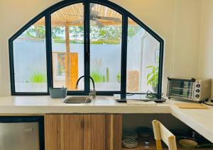 a kitchen with a sink and two large windows at Las Guapas Villas Tamarindo in Tamarindo