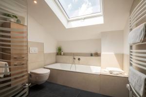 a bathroom with a tub and a toilet and a skylight at Ferienwohnung Am Moosbach in Übersee