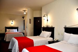 a hotel room with two beds with red and white sheets at Rosario Hotel in San Cristóbal de Las Casas
