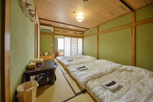 Habitación con 2 camas y mesa con mesa. en 芙蓉山居煙霞ー元富士の屋旅館ー en Fujikawaguchiko