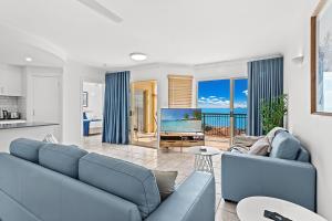 sala de estar con sofá azul y TV en Airlie Hasta Manana, en Airlie Beach