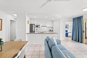 Airlie Hasta Manana في شاطئ إيرلي: غرفة معيشة مع أريكة زرقاء ومطبخ