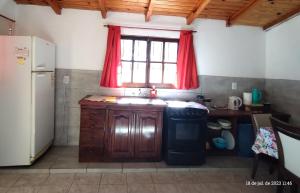 una cocina con fregadero y una ventana con cortinas rojas en Casa para 6 con cochera-Maragus en Posadas