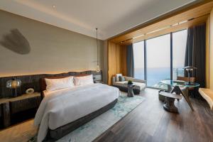um quarto com uma cama grande e uma janela grande em The Westin Yantai em Yantai