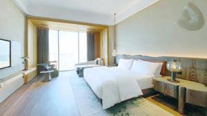 a bedroom with a white bed and a large window at The Westin Yantai in Yantai