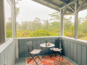 Hibiscus Hale, Full Kitchen, King Bed, Parking في Keaau: شاشة في الشرفة مع طاولة وكرسيين