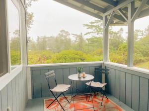 a screened in porch with a table and two chairs at Hibiscus Hale, Full Kitchen, King Bed, Parking in Keaau