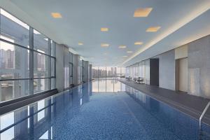 a large hallway with a pool in a building with windows at The Meixi Lake, Changsha Marriott Executive Apartments in Changsha