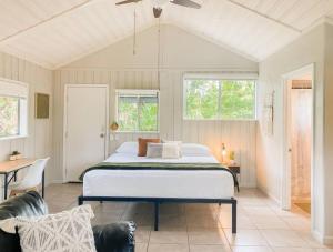 a bedroom with a bed and a table and windows at Monstera Bungalow, Spacious, King Bed, Big Kitchen in Keaau