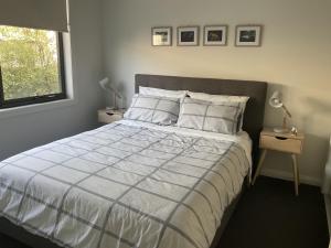 a bedroom with a large bed with white sheets and a window at NAUTILUS in Point Lonsdale