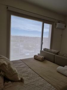a bedroom with a large window with a bed and a couch at Bella Vista in Cipolletti
