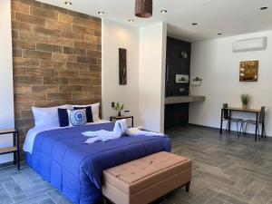 Un dormitorio con una cama azul y una pared de ladrillo en Antia Valle de Guadalupe en Valle de Guadalupe