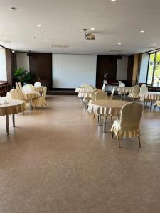 a large room with tables and chairs and a screen at Fuji Yamanakako Resort Hotel in Yamanakako
