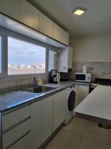 a kitchen with a sink and a microwave and a window at Bella Vista in Cipolletti