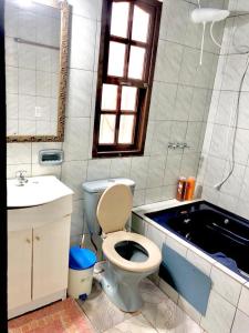 un bagno con un water, un lavandino e una vasca di Apart Belgrano a Puerto Iguazú Altre 32 foto